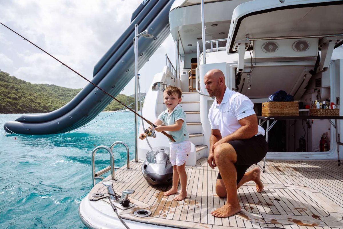 Father and young son fishing together off the stern of a luxury charter yacht in the British Virgin Islands