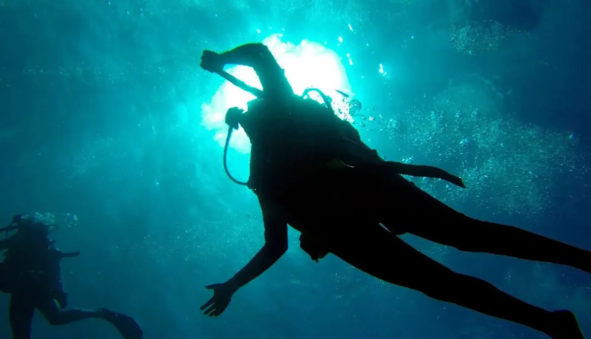 Scuba diver silhouetted against sun rays underwater in the British Virgin Islands