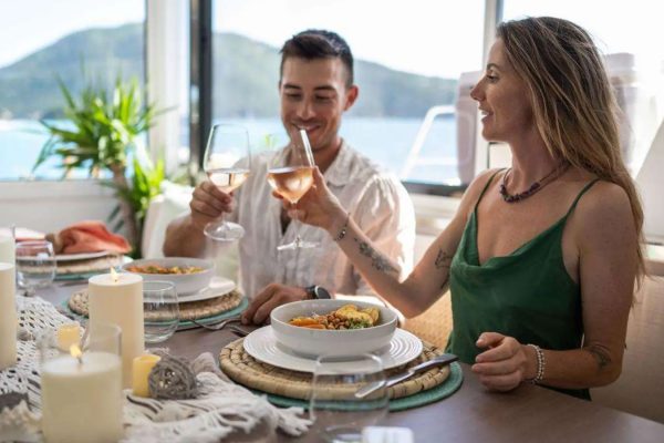 Guests enjoying a candlelit dinner toast aboard Elysian catamaran before their Virgin Islands yacht charter.